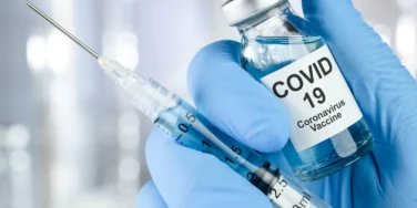 Healthcare with blue medical glove holding Covid 19 virus, vaccine vial