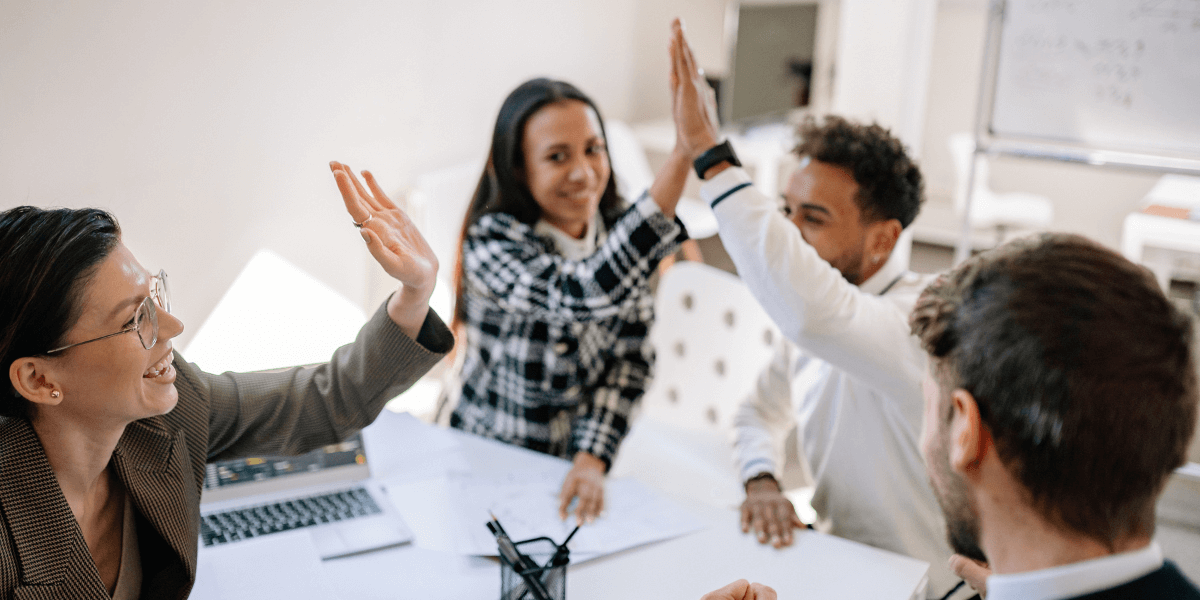 Team of employees high-fiving | Employee Benefits